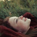A woman laying in the grass with her eyes closed