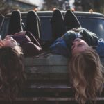two women lying down on vehicle